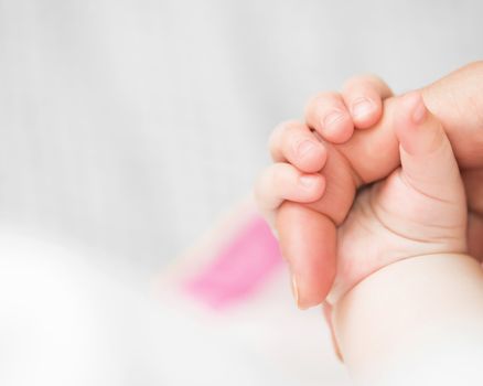 Close-up of baby's hand holding mother's finger