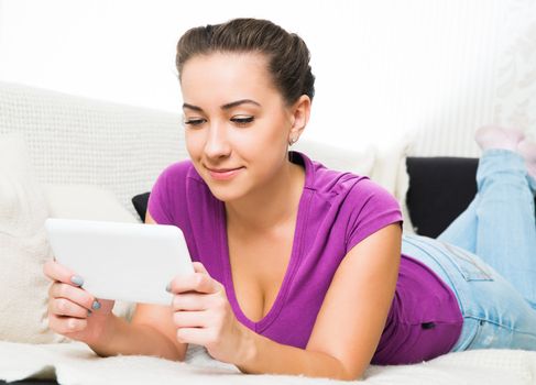 Young Brunette girl with tablet pc on the sofa.