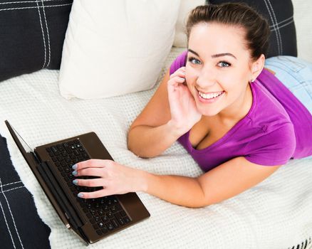Smiling attractive young woman using laptop at home