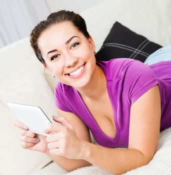 Smiling student girl with tablet pc on the sofa.