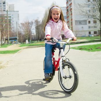 Smiling little girl on a bicycle in park