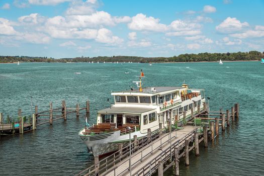 Passenger ship on lake Chiemsee in Germany with sailboat and bright sun.