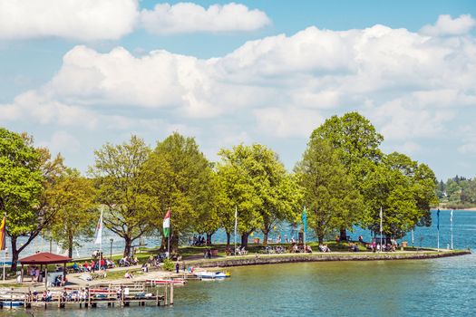 People at lake Chiemsee in Germany with paddleboats and bright sun.