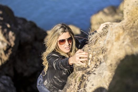 Sexy 007 girl climbing a rock wearing sunglasses.