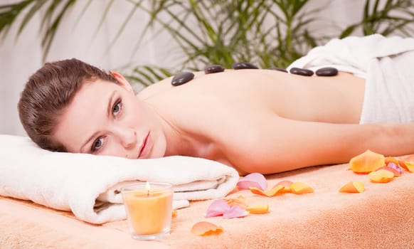 young attractive woman get hot stone massage by professional in wellness spa salon