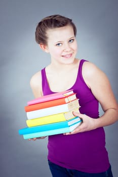 Silly smiling schoolgirl with glasses and lots of books having fun