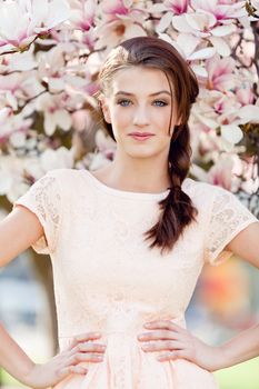 beautiful smiling woman and pink magnolia outside in spring