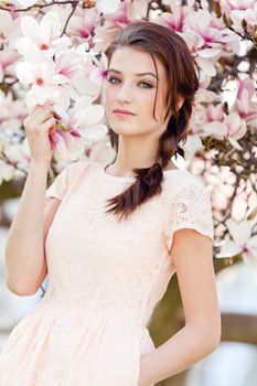 beautiful smiling woman and pink magnolia outside in spring