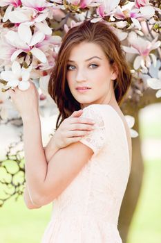 beautiful smiling woman and pink magnolia outside in spring
