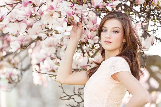 beautiful smiling woman and pink magnolia outside in spring