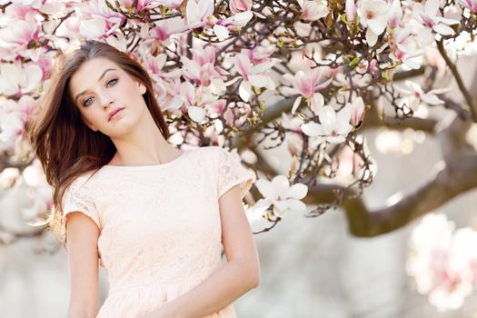 beautiful smiling woman and pink magnolia outside in spring