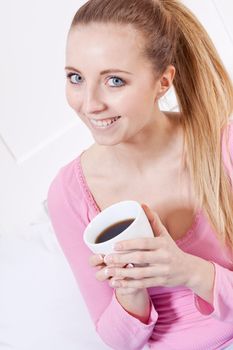 smiling young woman drinking coffee in the morning