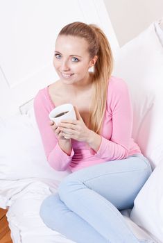 smiling young woman drinking coffee in the morning
