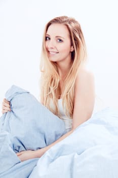 cute smiling blonde woman in the morning under blue blanket