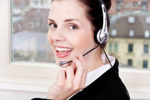 smiling young female callcenter agent with headset in office