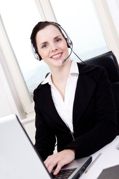 smiling young female callcenter agent with headset in office
