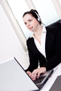smiling young female callcenter agent with headset in office