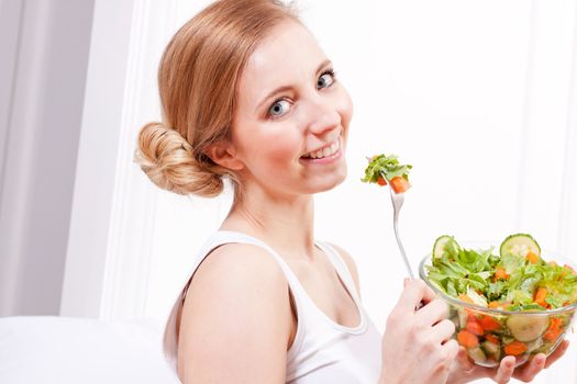 attractive young woman eating fresh healthy salad for lunch
