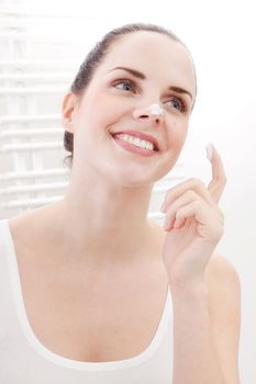 beautiful attractive woman applying cream on face skincare
