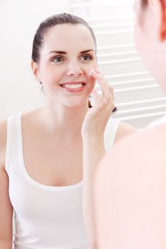 beautiful attractive woman applying cream on face skincare