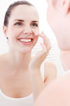 beautiful attractive woman applying cream on face skincare
