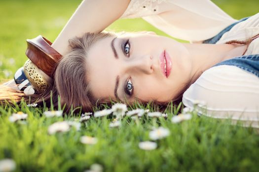 beautiful woman lying in grass with flowers in summer outdoor
