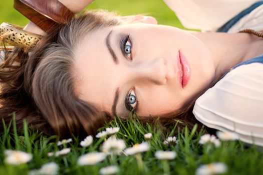 beautiful woman lying in grass with flowers in summer outdoor