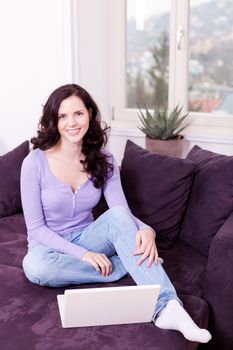 attractive young smiling woman on couch with notebook 