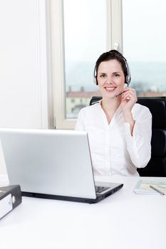 smiling young female callcenter agent with headset in office