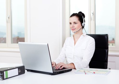 smiling young female callcenter agent with headset in office