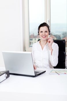 smiling young female callcenter agent with headset in office