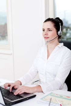 smiling young female callcenter agent with headset in office