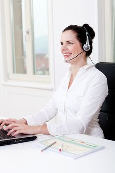 smiling young female callcenter agent with headset in office