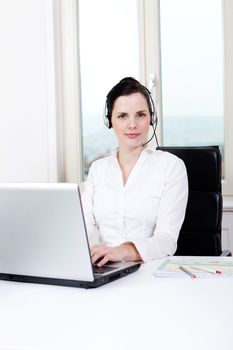 smiling young female callcenter agent with headset in office