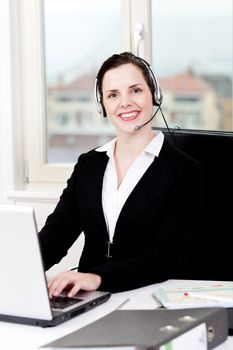 smiling young female callcenter agent with headset in office