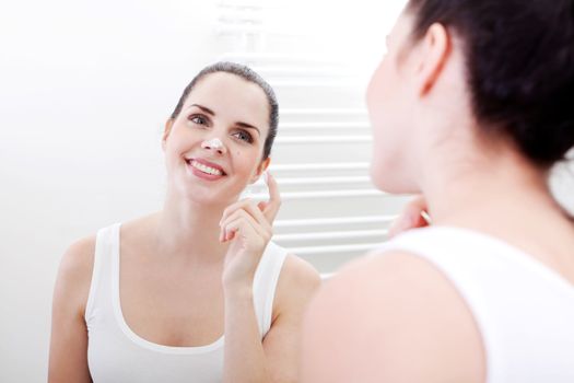 beautiful attractive woman applying cream on face skincare