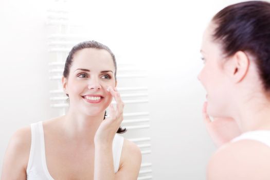 beautiful attractive woman applying cream on face skincare