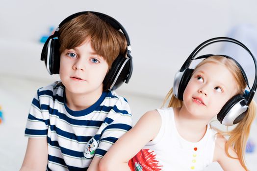 brother and sister listen to music in the living room with headphones