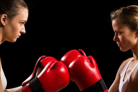 two female boxers face each other, pushing the boxing gloves, start a fight