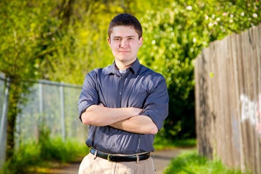 A college student business professional is photographed outside with natural light to create a portrait of a person wearing a grey shirt looking confident.