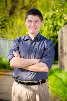 A college student business professional is photographed outside with natural light to create a portrait of a person wearing a grey shirt looking confident.