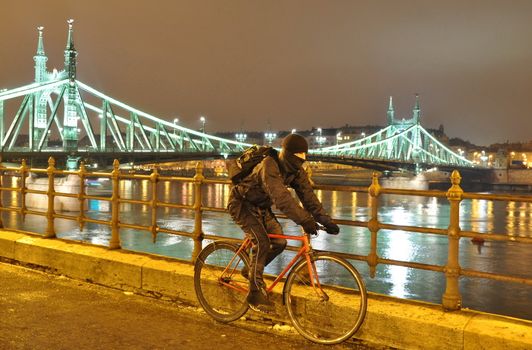 Cyclist moving next to river Danube at night