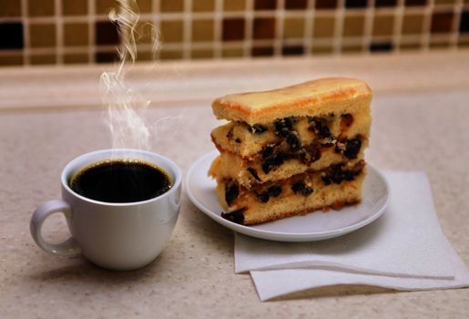 tasty cake with raisins and coffee cup on table