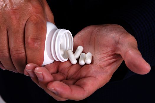 Mans hands shaking out some medicine from a pill bottle.