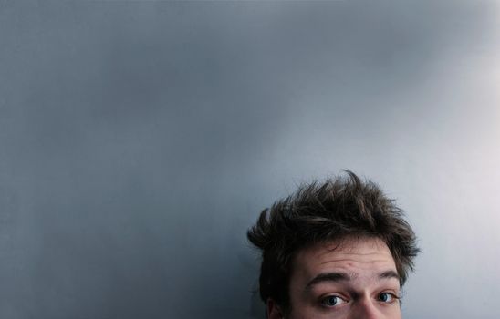 Funny morning look of a young adult men with on a white (greenish/blueish) background - not "isolated". This is also the Hangover or just "a bad night" look. You can see a bit of fatigue.