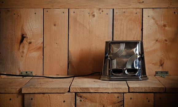 Old classic toaster on a nice cedar plank of wood texture. Warm and calm ambiance. Using ambient light (sunlight), it gives to this image a more natural look.