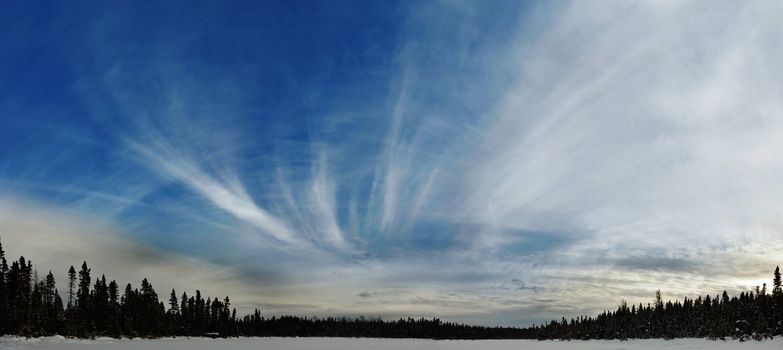 A nice panoramic view on a frozen lake with a beautiful sky with light clouds.