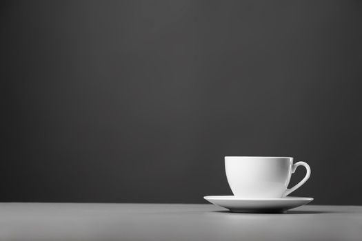 White mug and saucer on a gray background.