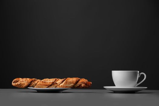 White mug and a baguette on a gray background.