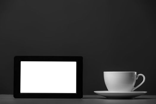 White mug and tablet computer on a gray background.